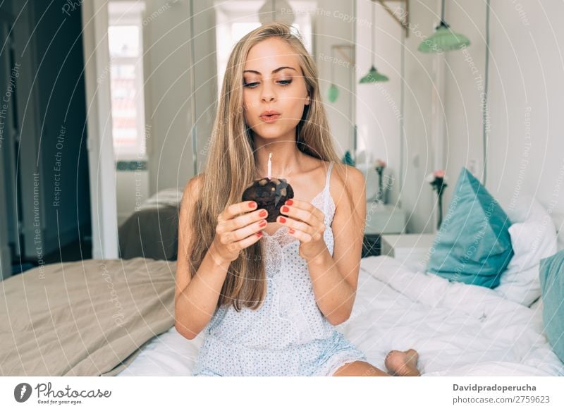Young beautiful blonde woman in the bed blowing a candle in a chocolate muffin Woman Bed Bedroom Blonde Portrait photograph Muffin Cake Blow Candle Birthday