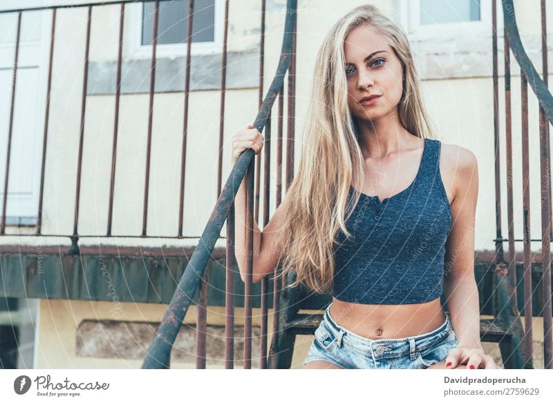 Young fit beautiful blonde woman sitting on the stairs posing Woman Portrait photograph Smiling Youth (Young adults) Considerate pretty Athletic Stairs Sit Blue
