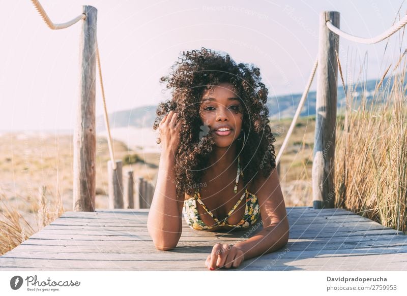 Beautiful young black woman lying down in a  wooden foot bridge at the beach Background picture Beach Bikini Black Bridge Coast Curly hair Destination Girl Cute