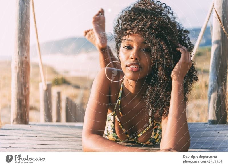 Beautiful young black woman lying down in a  wooden foot bridge at the beach Background picture Beach Bikini Black Bridge Coast Curly hair Destination Girl Cute