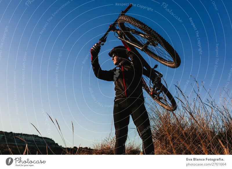 Cyclist holding the Bike at Sunset. Sports Lifestyle Relaxation Leisure and hobbies Adventure Summer Mountain Cycling Masculine Young man Youth (Young adults)