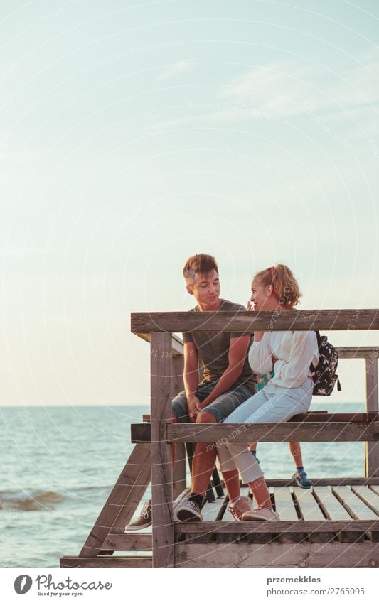 Smiling young woman and man sitting on a pier over the sea Lifestyle Joy Happy Leisure and hobbies Vacation & Travel Summer Ocean Human being Boy (child) Couple