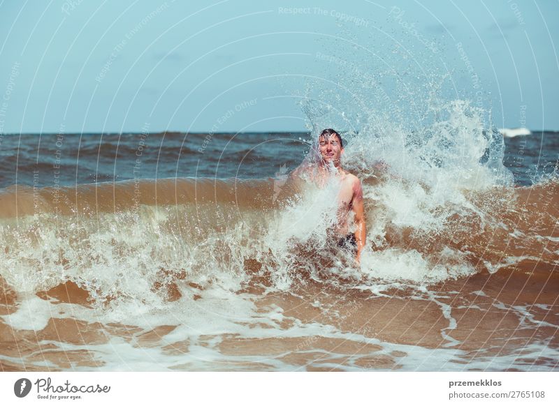 Young man enjoying the high waves in the sea during a summer vacations. Spending a summer holiday by the sea Lifestyle Joy Happy Relaxation Leisure and hobbies