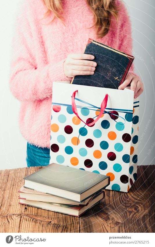 Young girl putting the books into paper bag in bookstore Lifestyle Relaxation Leisure and hobbies Reading School Study Human being Woman Adults