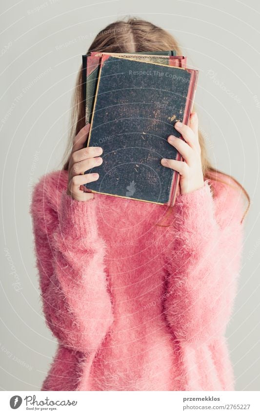 Young girl holding books in front of her face Lifestyle Joy Relaxation Leisure and hobbies Reading School Study Human being Woman Adults Youth (Young adults) 1