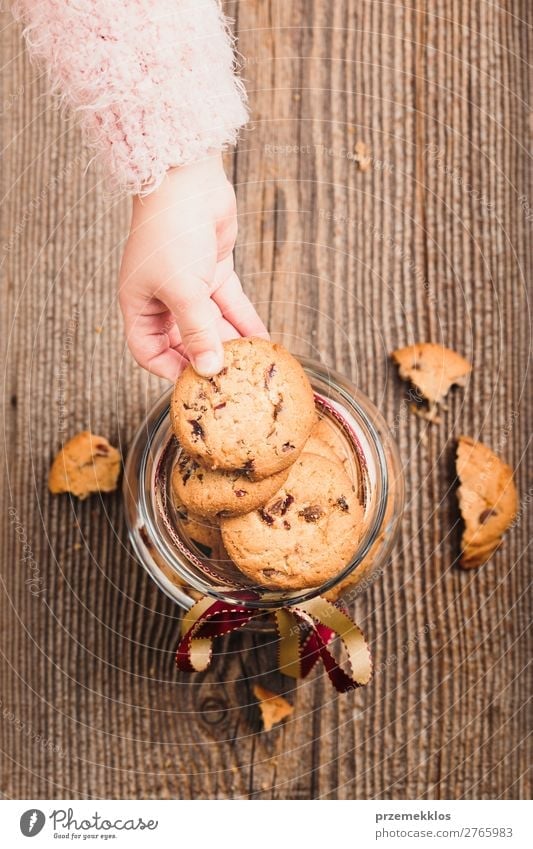 Little girl taking a cookie from a jar filled with oat cookies Dessert Nutrition Eating Diet Lifestyle Table Child Woman Adults Hand To enjoy Delicious Brown