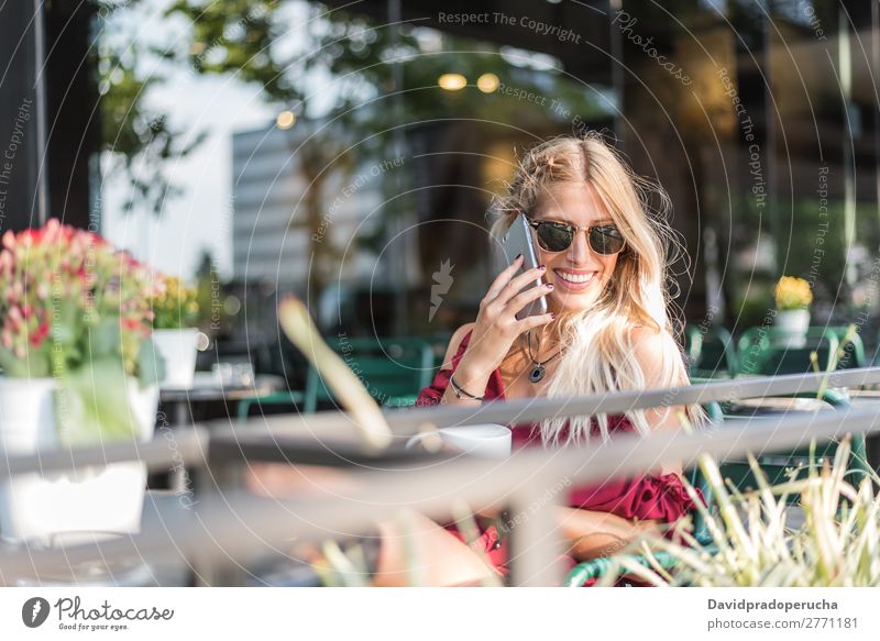 Happy blonde beautiful woman using a mobile phone drinking a cup of coffee in a terrace Woman Smiling Coffee Cup Cellphone PDA Sunglasses Terrace Restaurant