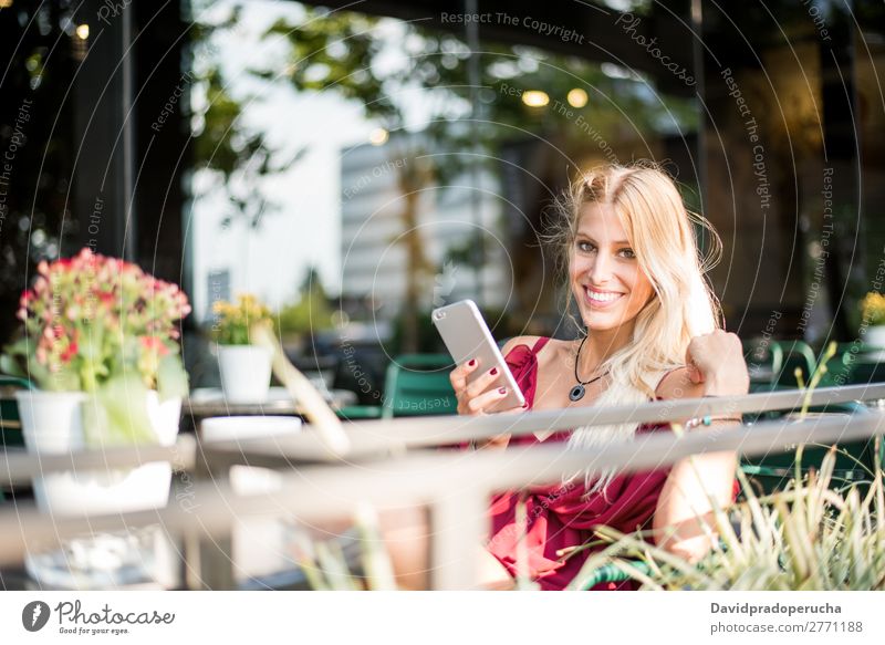 Happy blonde beautiful woman using a mobile phone drinking a cup of coffee in a terrace Woman Smiling Coffee Cup Cellphone PDA Sunglasses Terrace Restaurant