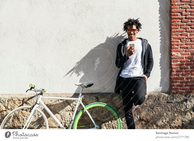 Afro young man using mobile phone and fixed gear bicycle. Man Youth (Young adults) African Black mulatto Mobile Bicycle fixie Telephone Lifestyle Stand Cycling