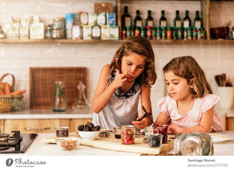 Little sisters girl preparing baking cookies. Child Girl Cooking Kitchen Chocolate tasting savoring Fingers Ice cream Strawberry Daughter Day Happy Joy