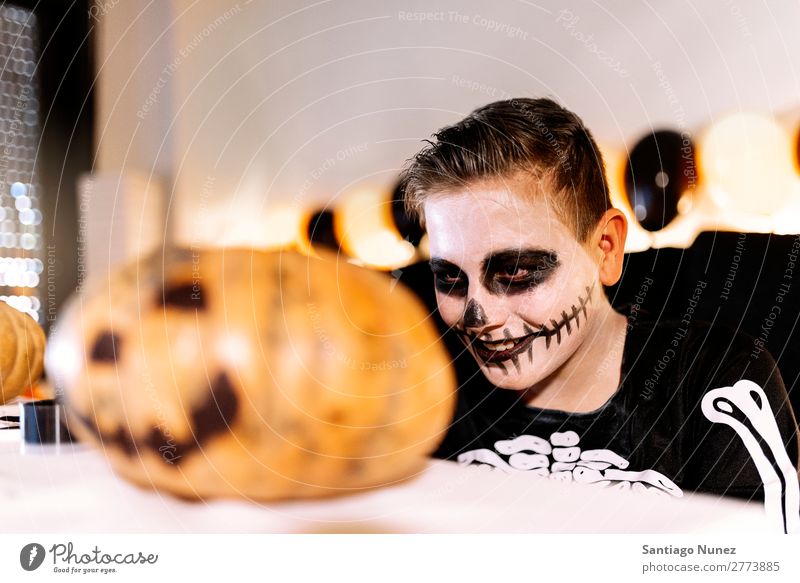 Happy boy disguised decorating a pumpkin at home. Hallowe'en Child Boy (child) Painting (action, artwork) Skeleton Joy Disguised Family & Relations Brother