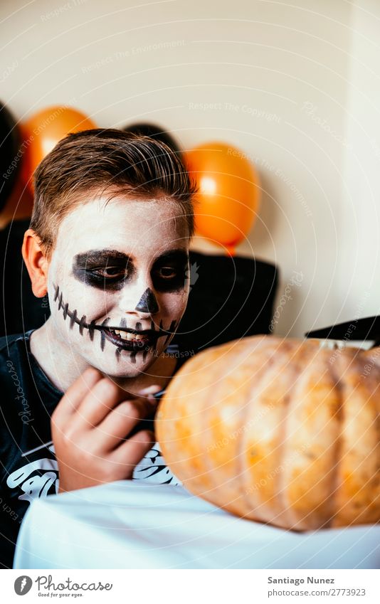 Happy boy disguised decorating a pumpkin at home. Hallowe'en Child Boy (child) Painting (action, artwork) Skeleton Joy Disguised Family & Relations Brother