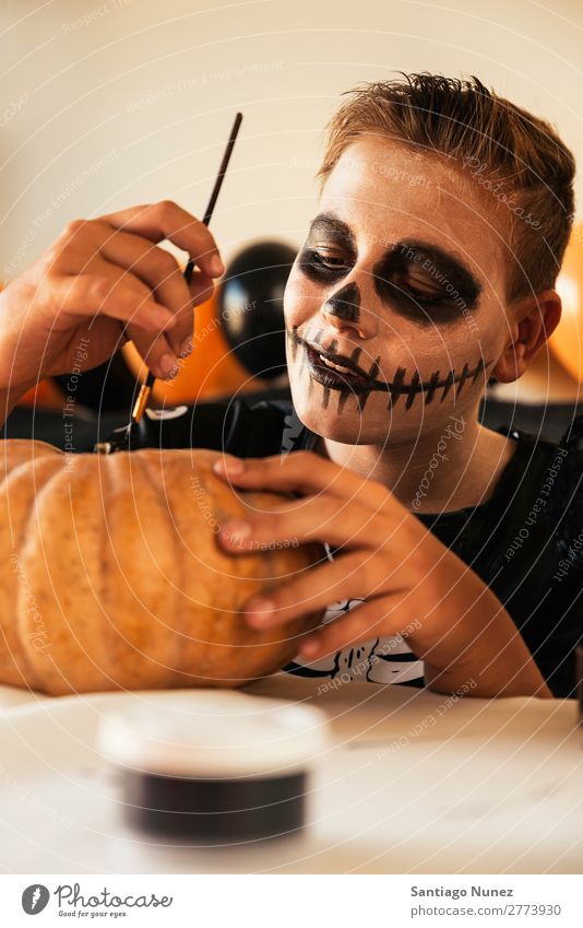 Happy boy decorating a pumpkin at home. Hallowe'en Child Boy (child) Painting (action, artwork) Skeleton Joy Disguised Family & Relations Brother