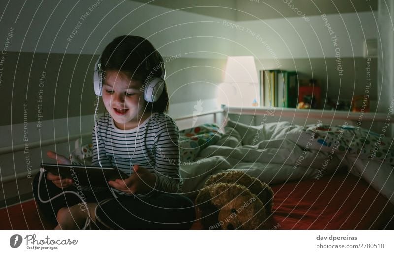 Girl with headphones looking at the tablet Lifestyle Joy Happy Beautiful Face Playing Lamp Bedroom Child Technology Internet Human being Woman Adults Infancy