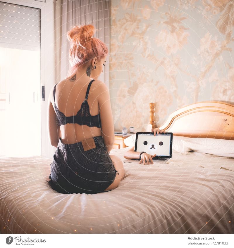 Young woman in black bra looking at laptop Woman Eroticism Notebook Illustration Screen Eyes Hand nobody's Bed Bedroom Sit Tattoo Neck Back Rear view Vertical