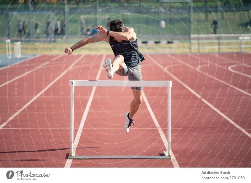 Man jumping over hurdle Running Hurdle Racecourse Athlete Track Determination Competition competitive Runner Speed Field hurdling compete Exterior shot sprint