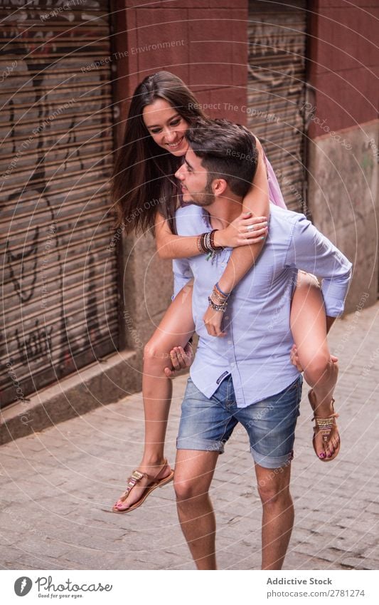 Smiling girl rides on back of boyfriend Couple Ride Girl Back Woman Man girlfriend Hold City Human being Cheerful Hip & trendy piggyback Youth (Young adults)