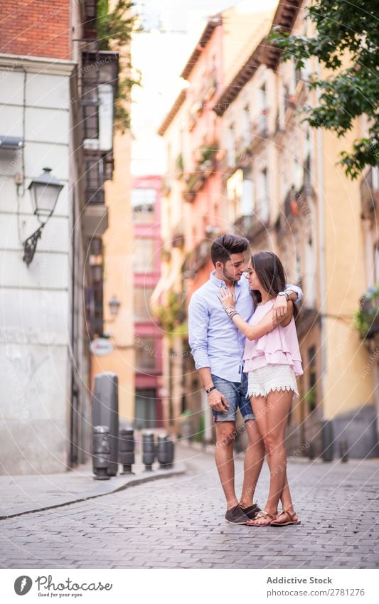 Boyfriend embracing his girlfriend in the street Couple Street Romance Portrait photograph Face to face Building Facade Background picture Easygoing Full-length