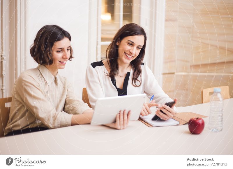 Young women looking at tablet and smiling Woman Smiling Tablet computer Communication Technology Cheerful Indicate using Business small business Entrepreneur