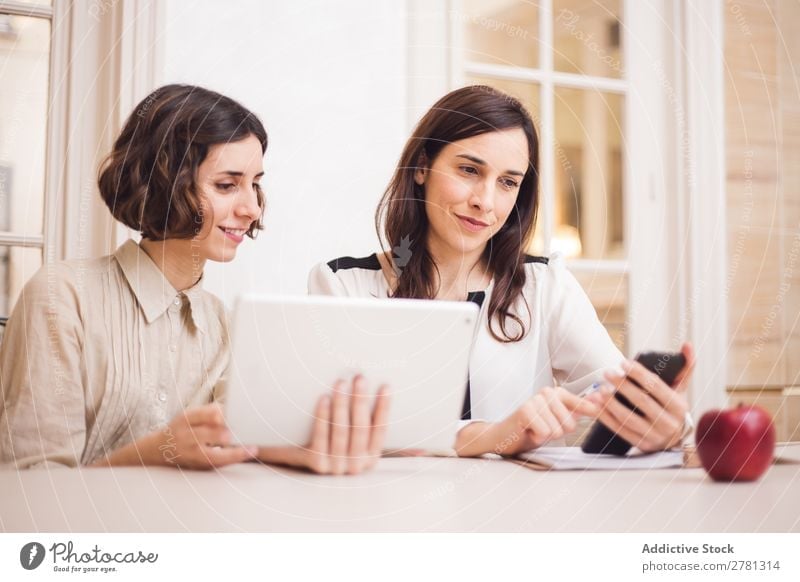 Young women looking at tablet and smiling Woman Smiling Tablet computer Communication Technology Cheerful Indicate using Business small business Entrepreneur