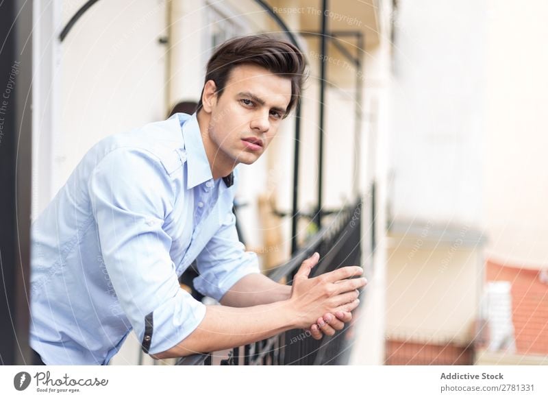 Young serious man in blue shirt posing Man Earnest Stand Balcony Portrait photograph Gesture Considerate Pensive Posture Human being 1 Youth (Young adults)