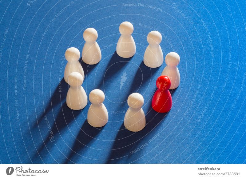 A red playing figure stands together with white playing figures in a circle on a blue background Playing Piece Group Wood Friendliness Round Blue Red White