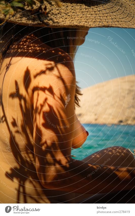 bare-breasted woman with straw hat on nudist vacation at Mediterranean Sea. Shadows cast by plants on naked skin Exotic Skin NUDISM Well-being Summer vacation