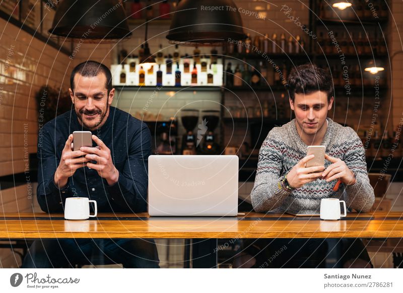 Friends using mobile and laptop. Man Coffee Friendship Youth (Young adults) Teamwork Group Human being Lifestyle PDA Cellphone Mobile Communication Text