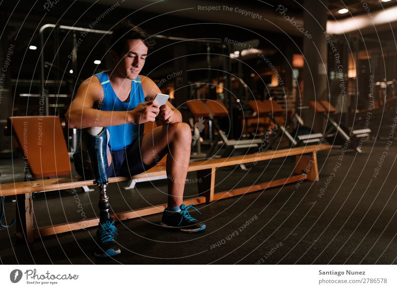 Disabled young man using his mobile in the gym. Man Youth (Young adults) Athlete Sports prothestic Portrait photograph Handicapped disabled paralympic Mobile