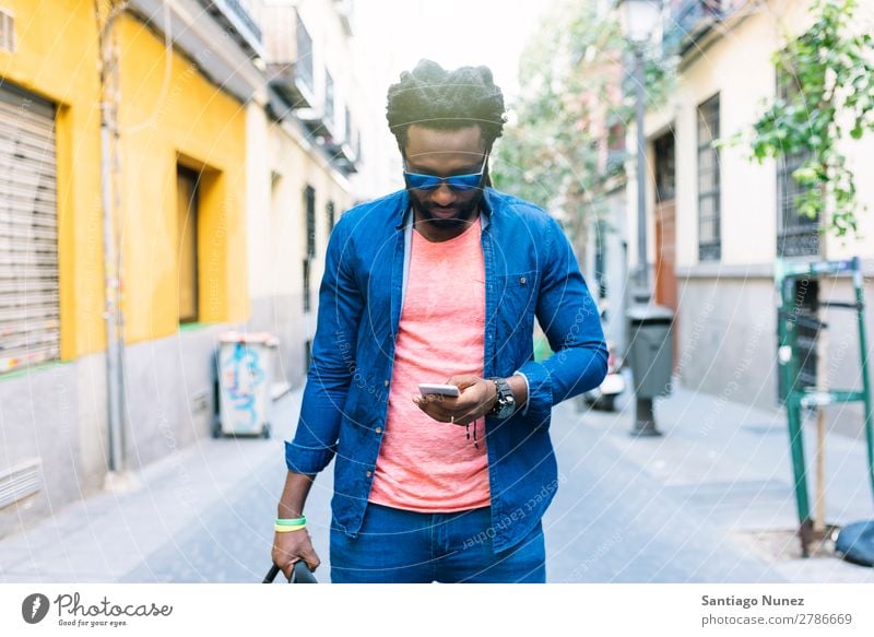 African Young Man Using Mobile In The Street. Lifestyle Listening Black American Town Portrait photograph Telephone PDA Solar cell Communication texting Email