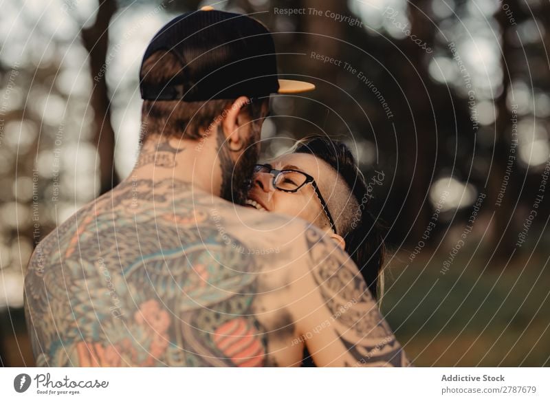 Young guy in tattoos hugging lady in forest Couple Tattoo Embrace Forest snapback Park Lady shirtless Guy Youth (Young adults) Hipster embracing Man Woman
