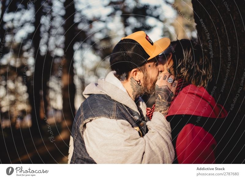 Happy couple hugging and kissing near tree in park Couple Embrace Park Tree embracing Back Wood Forest Youth (Young adults) Cheerful bearded Man Woman Joy