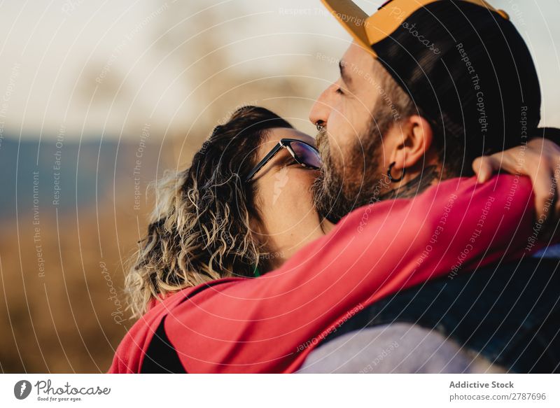 Young lady biting guy in tattoos Couple Tattoo Neck Eyeglasses Earring snapback Lady Guy Youth (Young adults) Hipster Man Woman embracing romantic Embrace Art