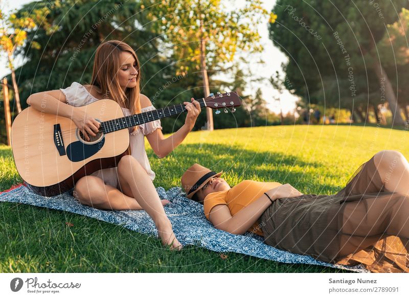 Beautiful women having fun playing guitar in the park. Woman Picnic Friendship Youth (Young adults) Park Happy Guitar Guitarist Summer Human being Joy Playing
