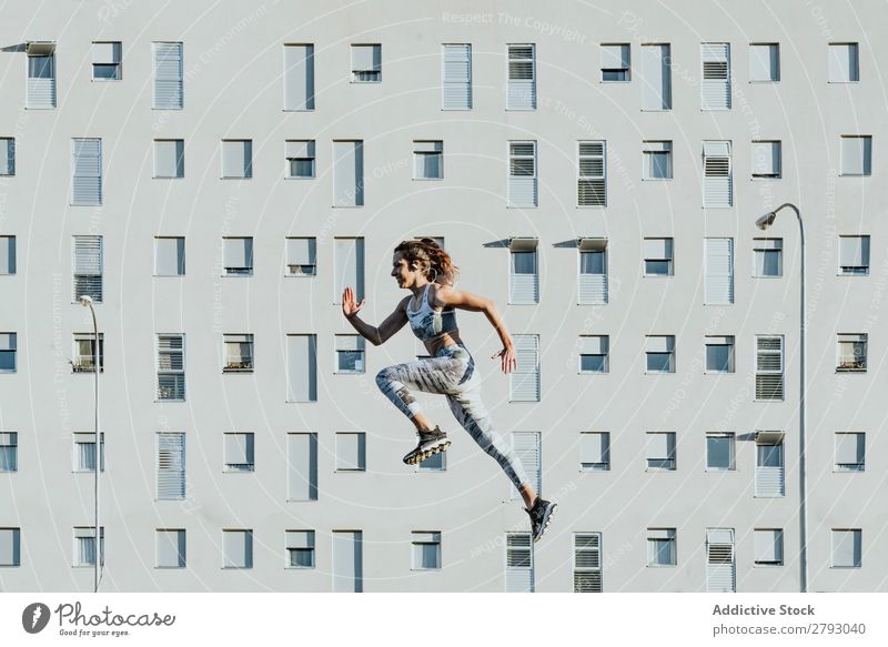 Woman in sportswear jumping near building Sports Jump Sportswear Building Athletic Sunbeam Weather Thin Lady levitating Flying Fitness Youth (Young adults)