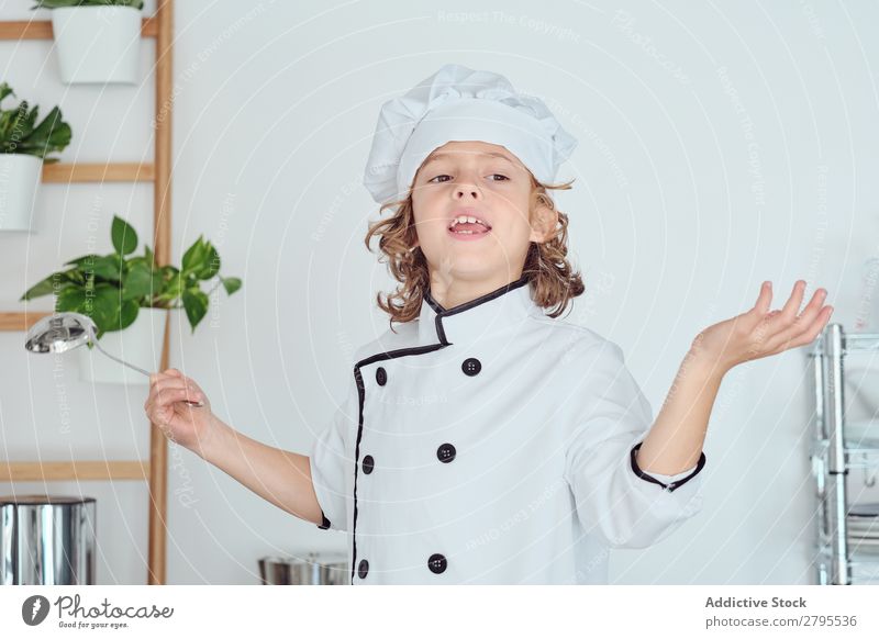 Boy in cook hat holding ladle and showing thumb up in kitchen Cook Boy (child) Kitchen Ladle chef Child Hat Cool (slang) Gesture Cooking Metal Modern Home