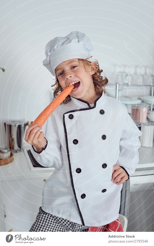 Boy in cook hat with carrot in kitchen Cook Boy (child) Kitchen Carrot chef Child Vegetable Hat Fresh Indicate Hand Hip Cooking Modern Funny Home Light