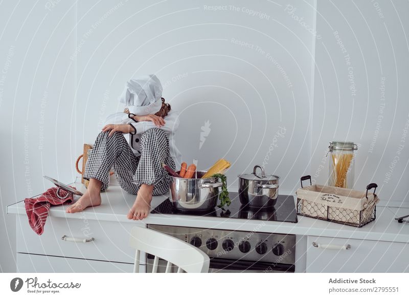 Boy in cook hat sitting near pots on electric fryer in kitchen Cook Boy (child) Pot Kitchen chef Child Vegetable Hat Stove & Oven Cooking Modern Funny Home