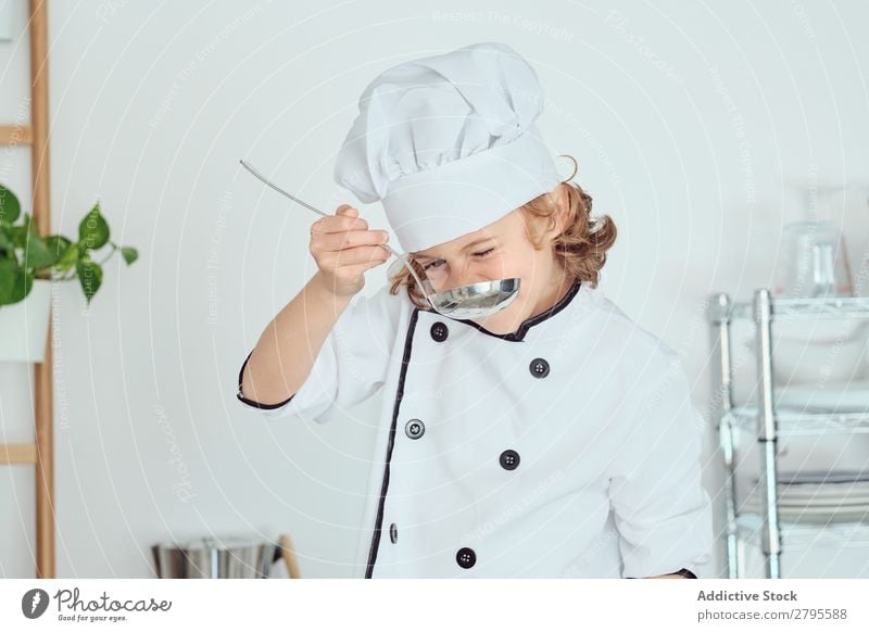 Boy in cook hat holding ladle near mouth in kitchen Cook Boy (child) Kitchen Ladle Mouth chef Child Pot tasting Food Hat Cooking Metal Modern Home Light
