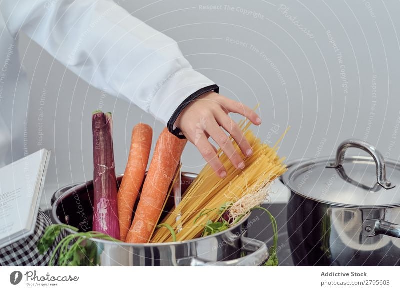 Boy near pot with vegetable and pasta on electric fryer in kitchen Cook Boy (child) Pot Pasta Vegetable Kitchen chef Child Hand Stove & Oven Cooking Putt Modern