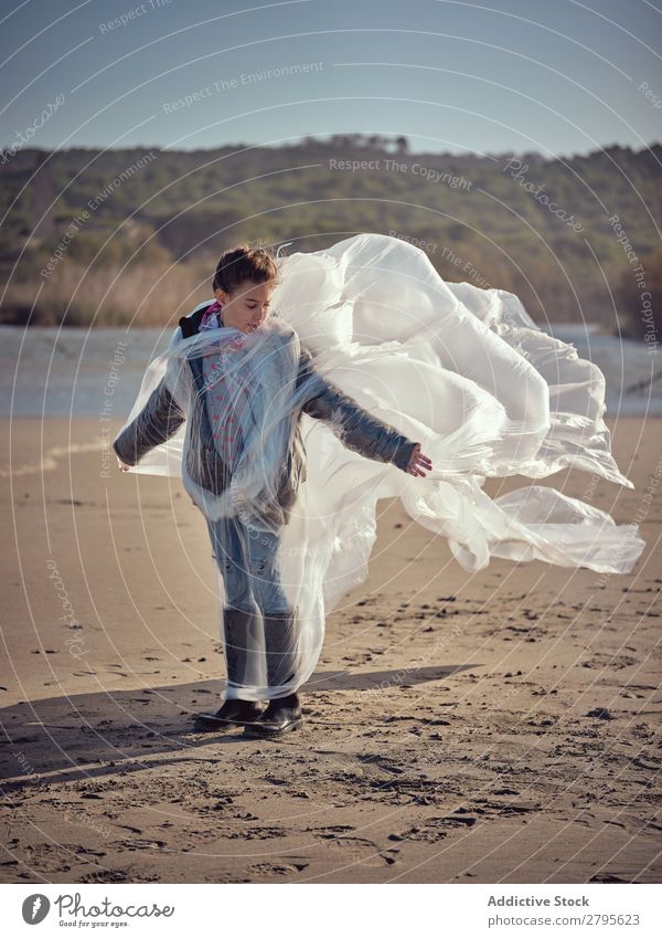 Girl entangled in plastic on river coast Plastic textile waving River Coast Side Wind Sand Water Mountain Landscape Beach Help White Sun Woman Joy Happiness