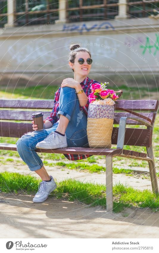 Front view of a young hipster woman sitting on a park bench relaxing in a sunny day while looking away Young woman Hipster Hip & trendy Sit Smiling Looking away