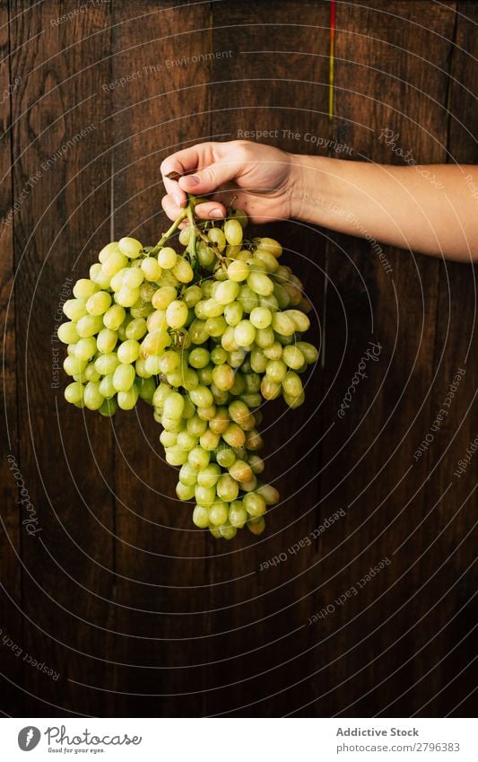 Crop hand with bunch of grapes Hand Bunch of grapes Wall (building) Wood Woman Fruit Harvest Plant Organic Seasons Autumn Natural Surface Timber Healthy Sweet
