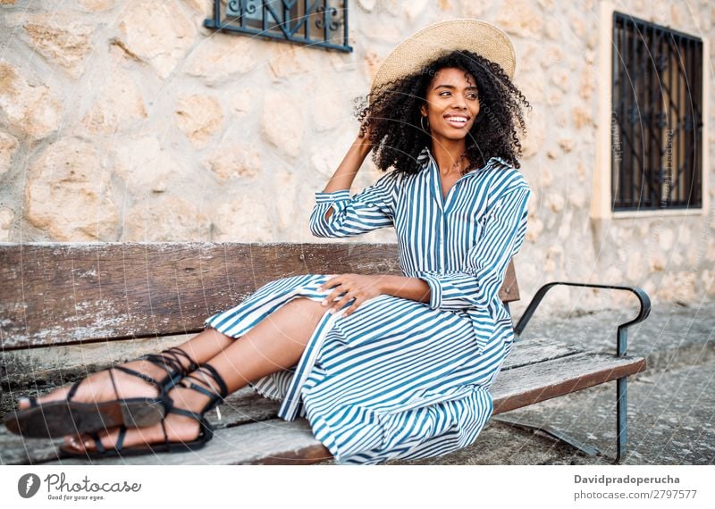 Woman sitting on a bench near a stone house Beauty Photography Close-up Ethnic Black Cheerful Sit Bench African Beautiful Smiling Straw hat Curly hair Happy