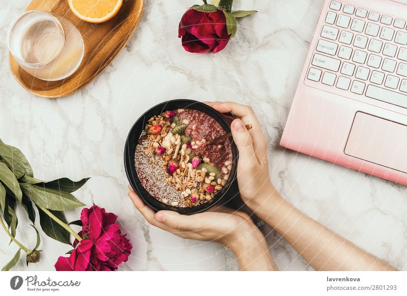 Hands holding smoothie bowl with laptop, peonies and water Notebook Orange Water Drinking water Fruit Milkshake chia pudding Diet Detox Bowl Young woman Snack