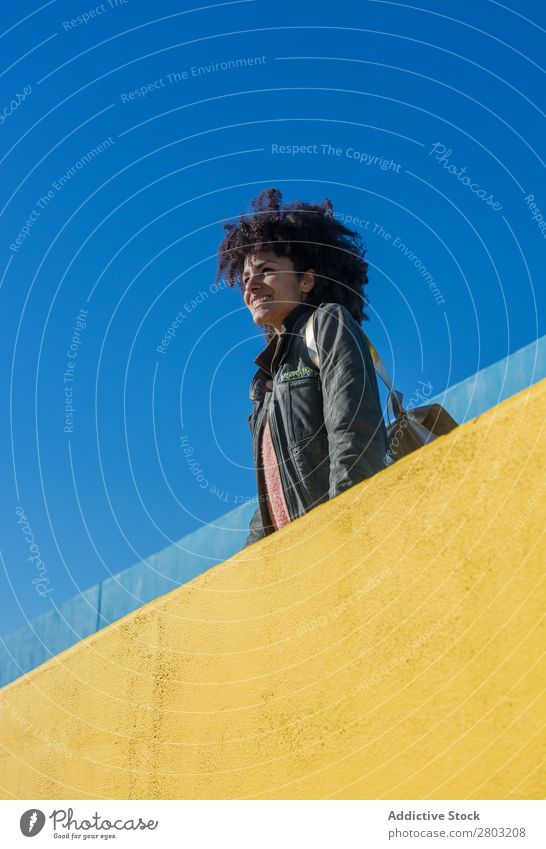 Black woman with afro hair leaning against brightly colored walls. Adults African Afro American Background picture Beautiful Beauty Photography Blue Easygoing