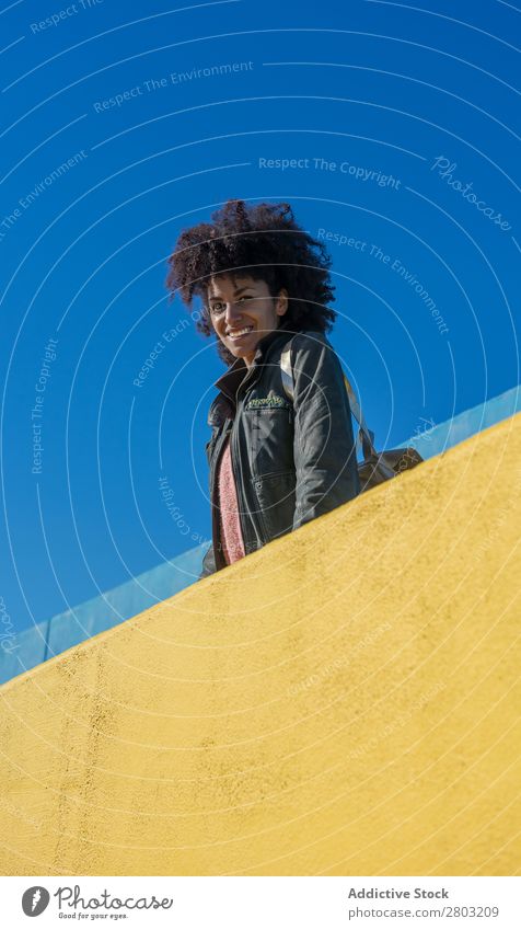 Black woman with afro hair leaning against brightly colored walls. Adults African Afro American Background picture Beautiful Beauty Photography Blue Easygoing