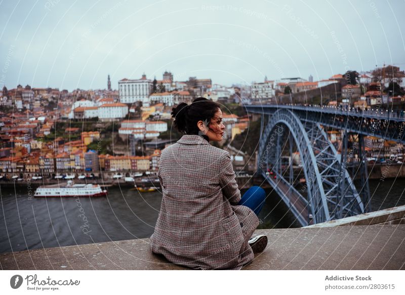 Stylish woman sitting near bridge in old city Woman Bridge City Old Tourism Looking away Sit River Porto Portugal Town Street Vacation & Travel Trip Rest