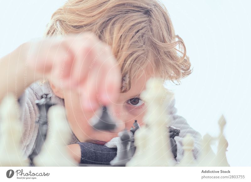 Boy holding figure on chess board Boy (child) Blonde Chess Chessboard Figure Table Playing Smart Indicate Child White Curtain Joy Leisure and hobbies Intellect
