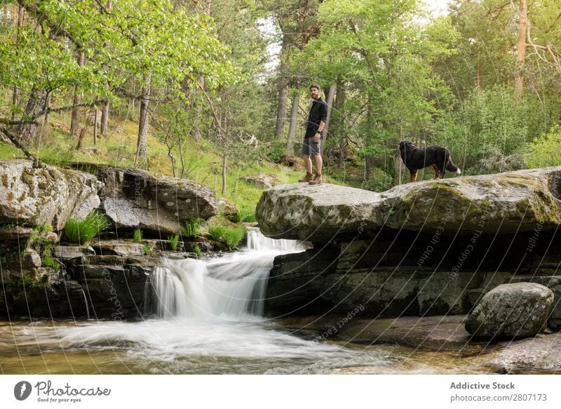 Young man enjoys rest at the waterfall after adventure with his dog Water Nature Summer Vacation & Travel Man Dog enjoying Waterfall Healthy Body